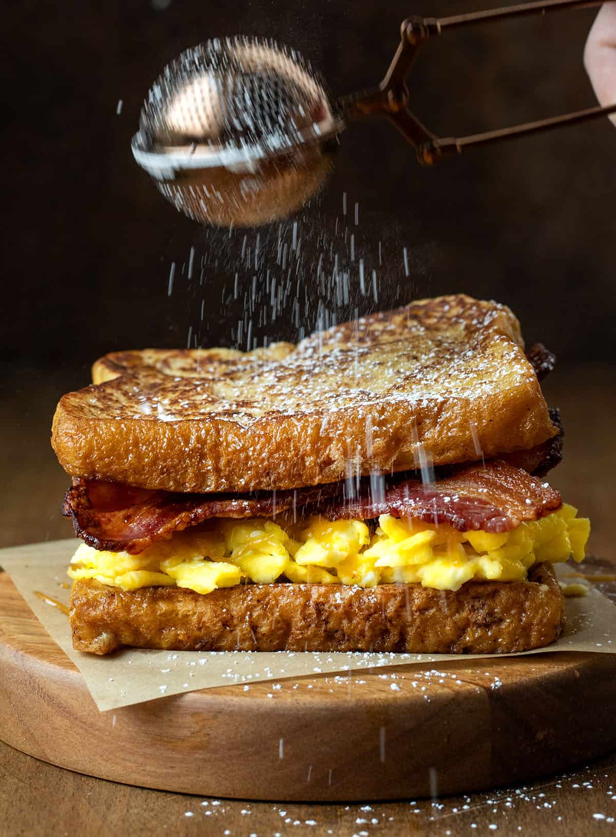 Dusting confectioners sugar over a French Toast Breakfast Sandwich Dusting confectioners sugar over a French Toast Breakfast Sandwich.