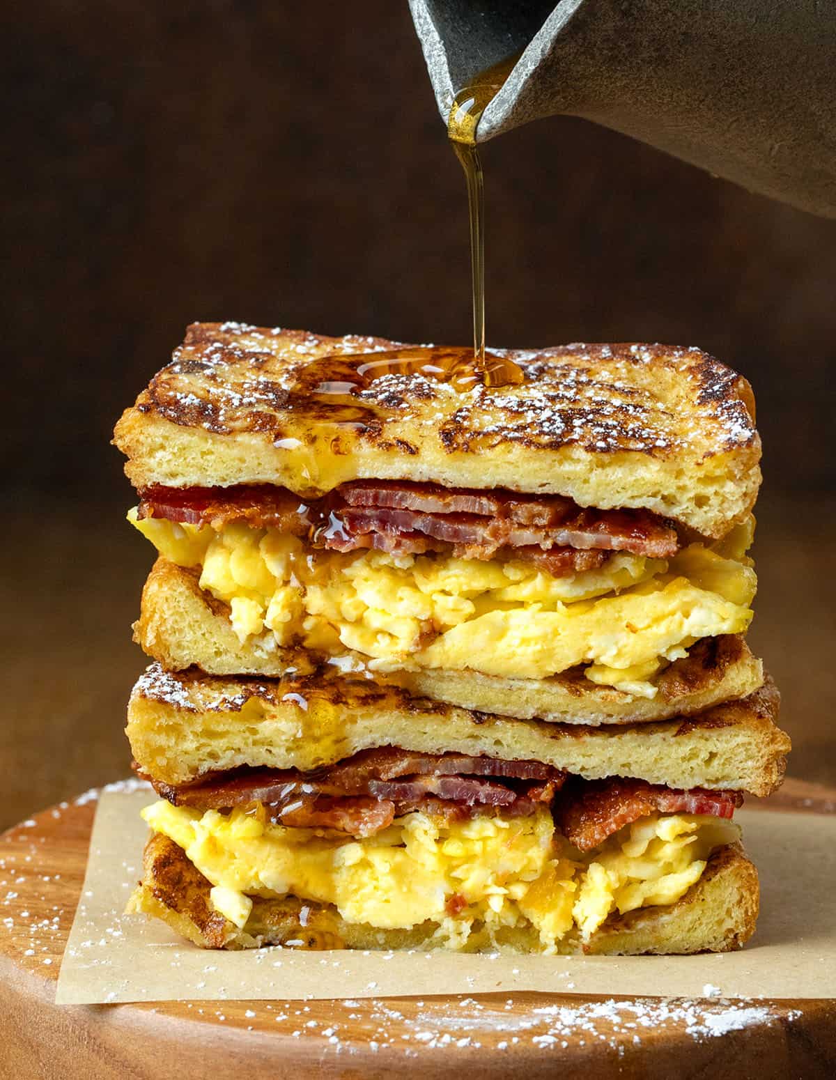 Drizzling syrup over a French Toast Breakfast Sandwich on a wooden table Drizzling syrup over a French Toast Breakfast Sandwich on a wooden table.
