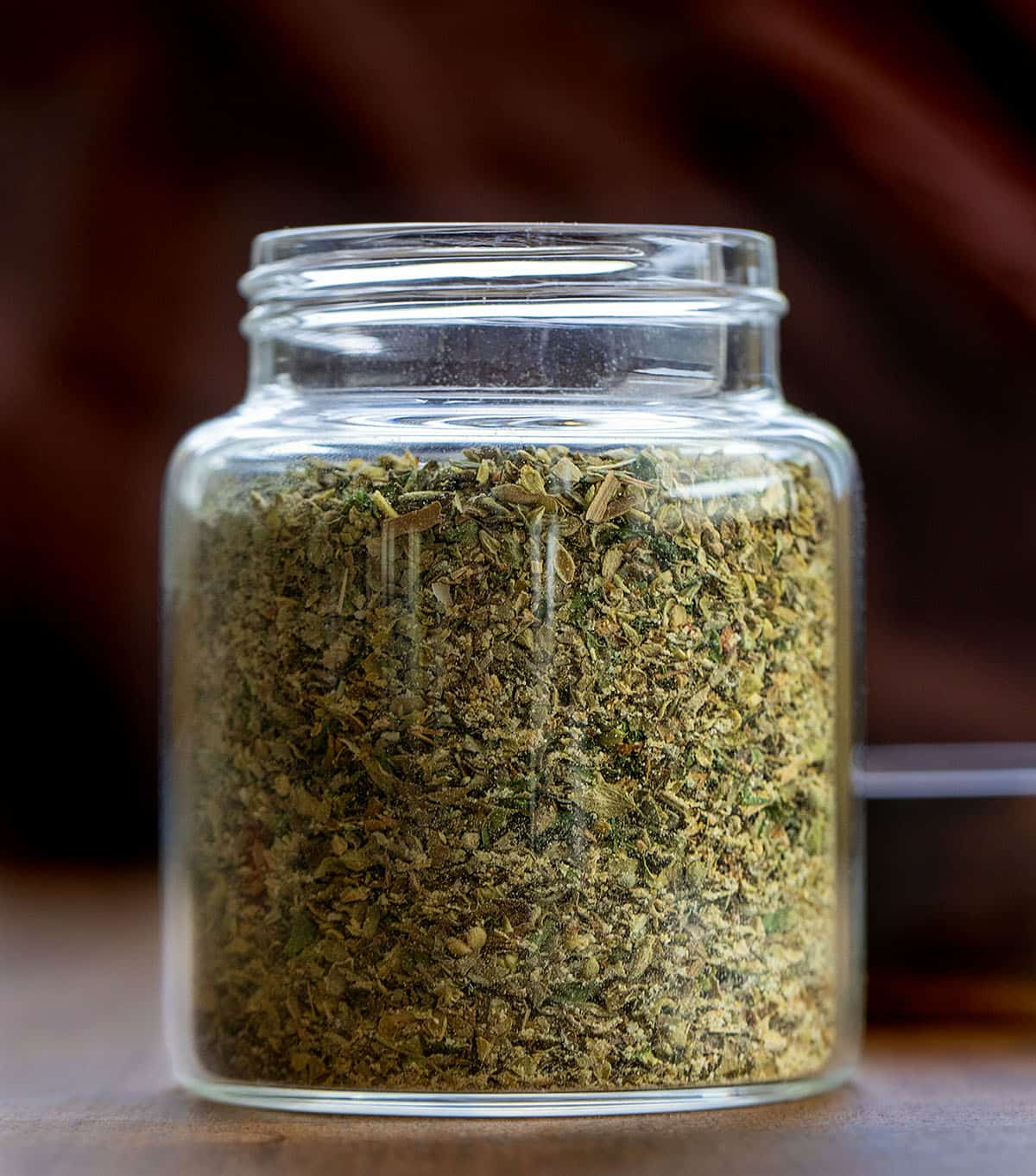 Glass jar of homemade Italian Seasoning on a wooden table Glass jar of homemade Italian Seasoning on a wooden table.