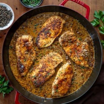 Skillet of Peppercorn Chicken on a wooden table from overhead.