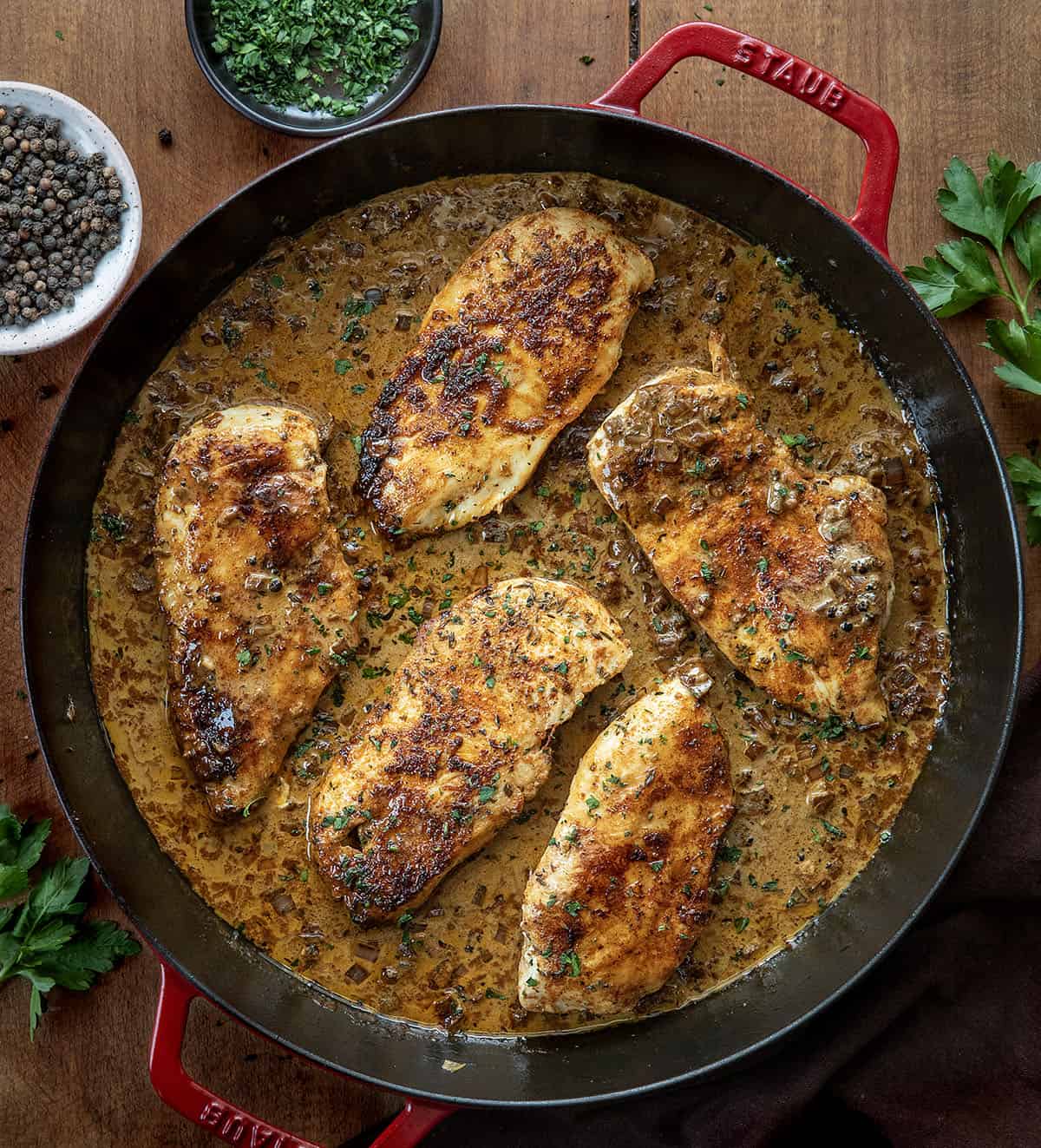Skillet of Peppercorn Chicken on a wooden table from overhead Skillet of Peppercorn Chicken on a wooden table from overhead.