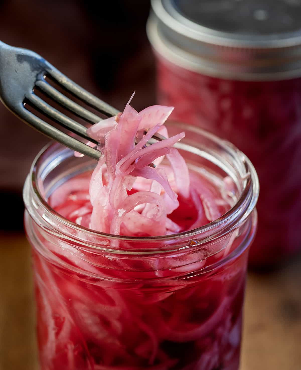 Fork picking up some Pickled Red Onions from jar Fork picking up some Pickled Red Onions from jar.