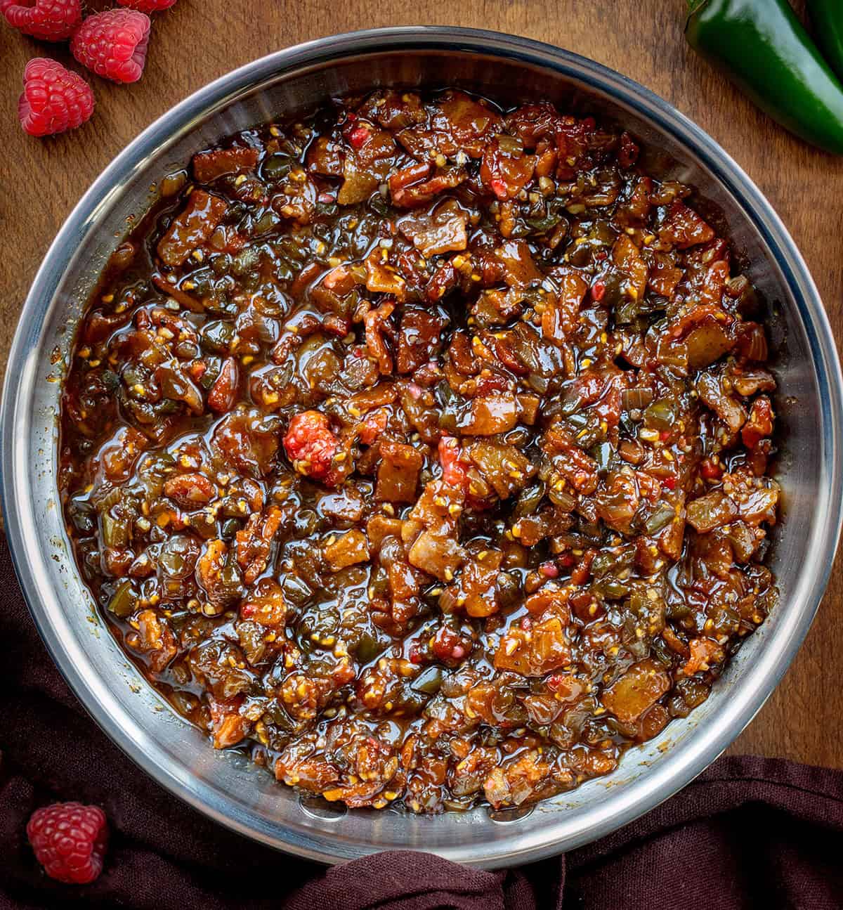 Pan of Raspberry Jalapeño Bacon Jam on a wooden table from overhead Pan of Raspberry Jalapeño Bacon Jam on a wooden table from overhead.