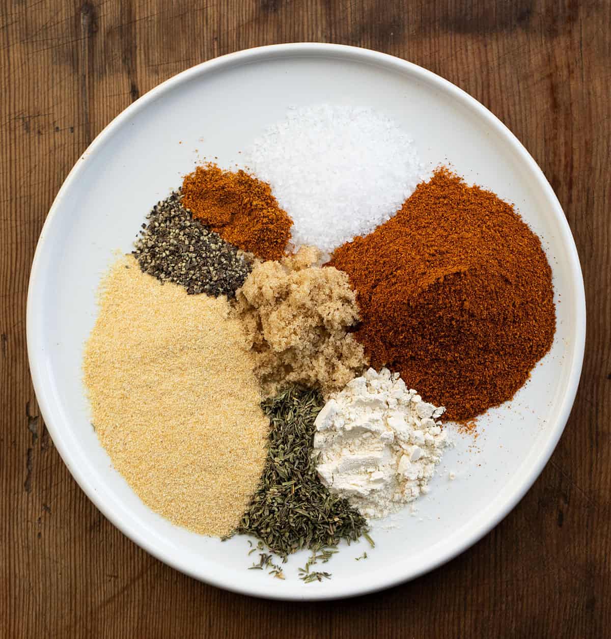 Plate with all of the seasonings used in Salmon Seasoning on a wooden table Plate with all of the seasonings used in Salmon Seasoning on a wooden table.