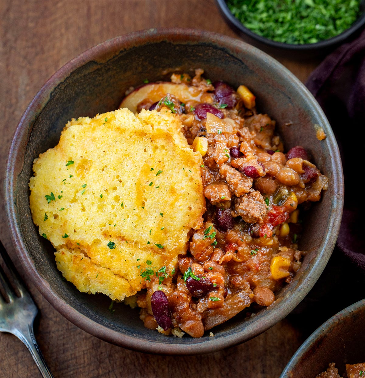 Bowl of Slow Cooker Cornbread Cowboy Casserole on a wooden table from overhead Bowl of Slow Cooker Cornbread Cowboy Casserole on a wooden table from overhead.