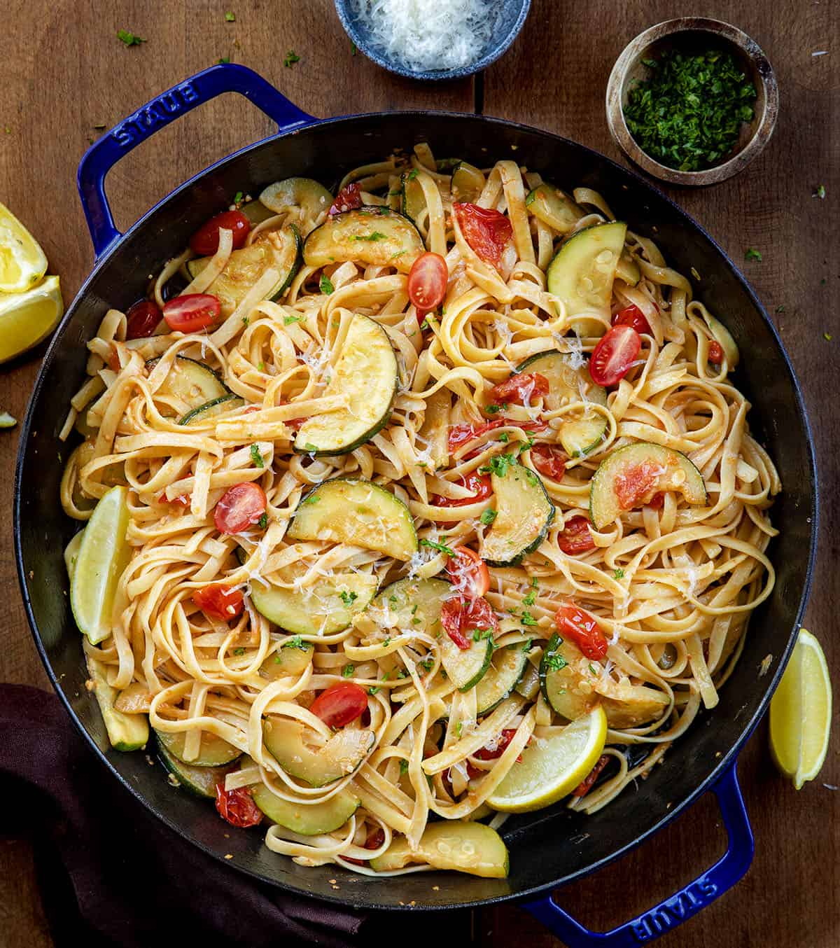 Skillet of Zucchini & Blistered Tomato Fettuccine on a wooden table from overhead Skillet of Zucchini & Blistered Tomato Fettuccine on a wooden table from overhead.