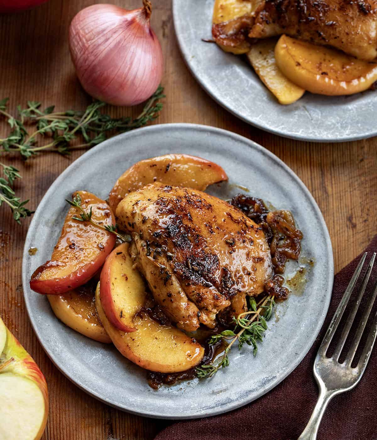 Plates of Apple Shallot Chicken on a wooden table from overhead Plates of Apple Shallot Chicken on a wooden table from overhead.