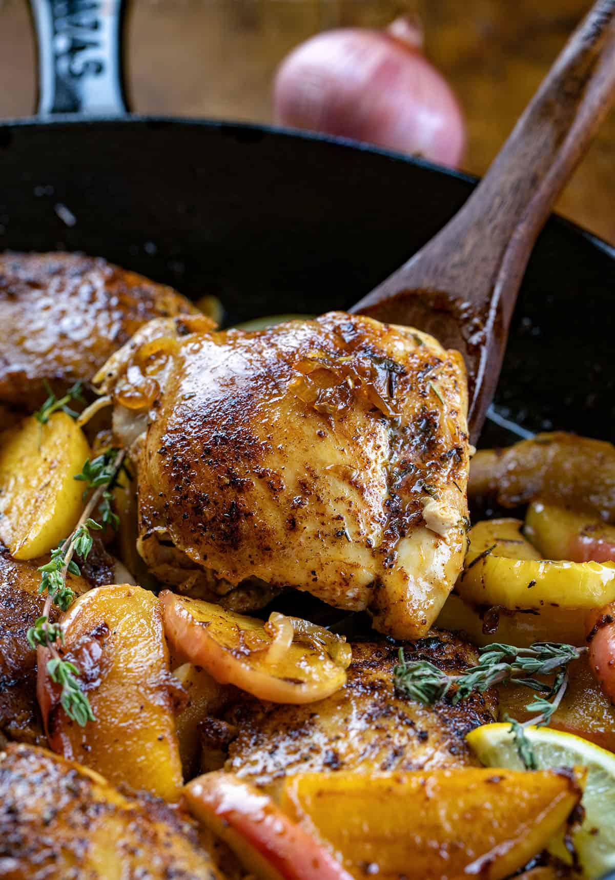 Wooden spoon holding up a piece of Apple Shallot Chicken Wooden spoon holding up a piece of Apple Shallot Chicken.