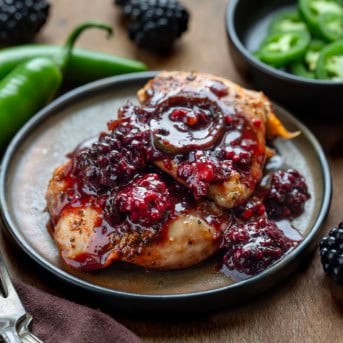 Plate with Blackberry Fire Chicken on it with peppers and blackberries around it.