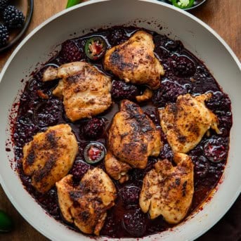 Skillet of Blackberry Fire Chicken on a wooden table from overhead.