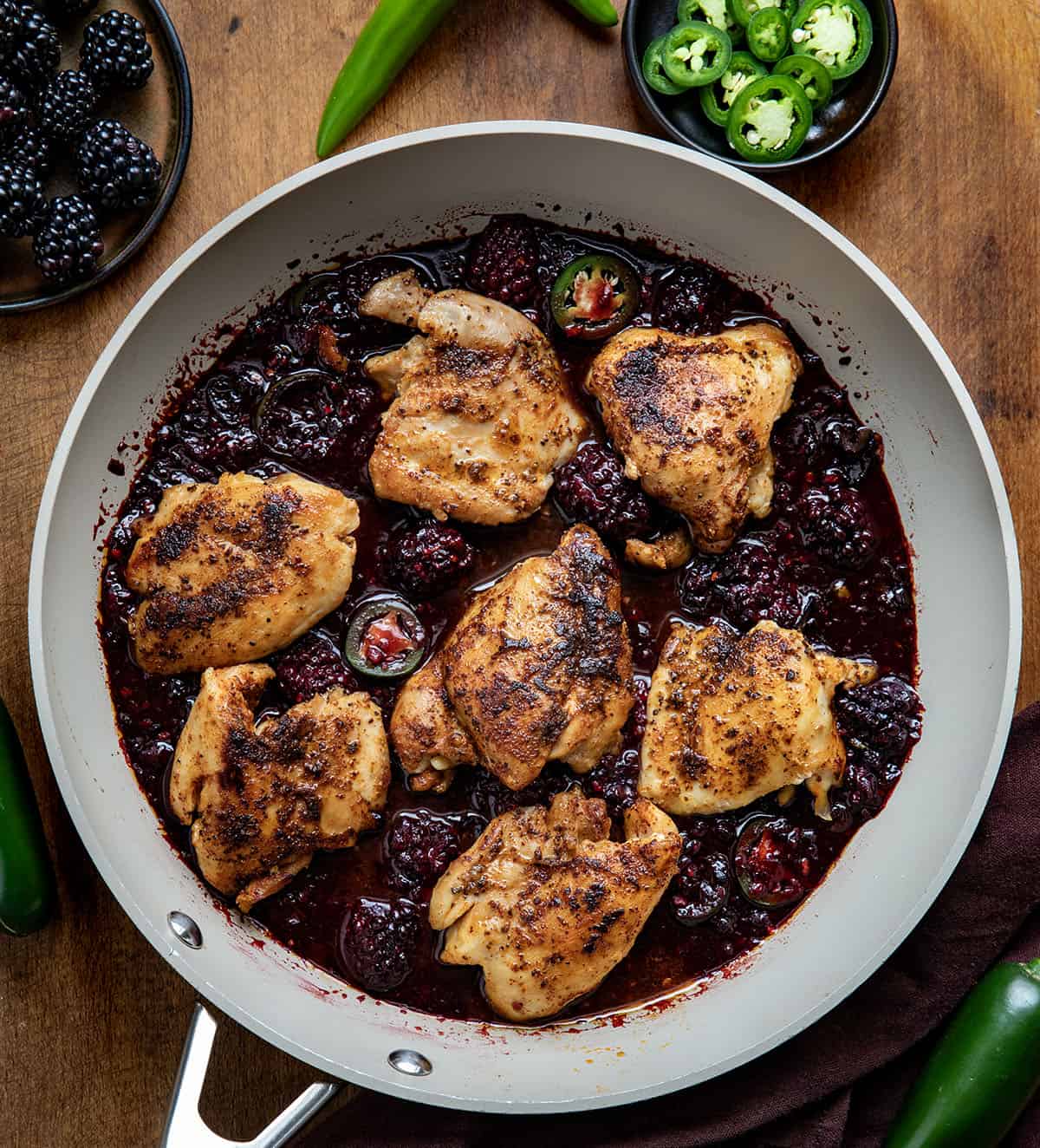 Skillet of Blackberry Fire Chicken on a wooden table from overhead Skillet of Blackberry Fire Chicken on a wooden table from overhead.