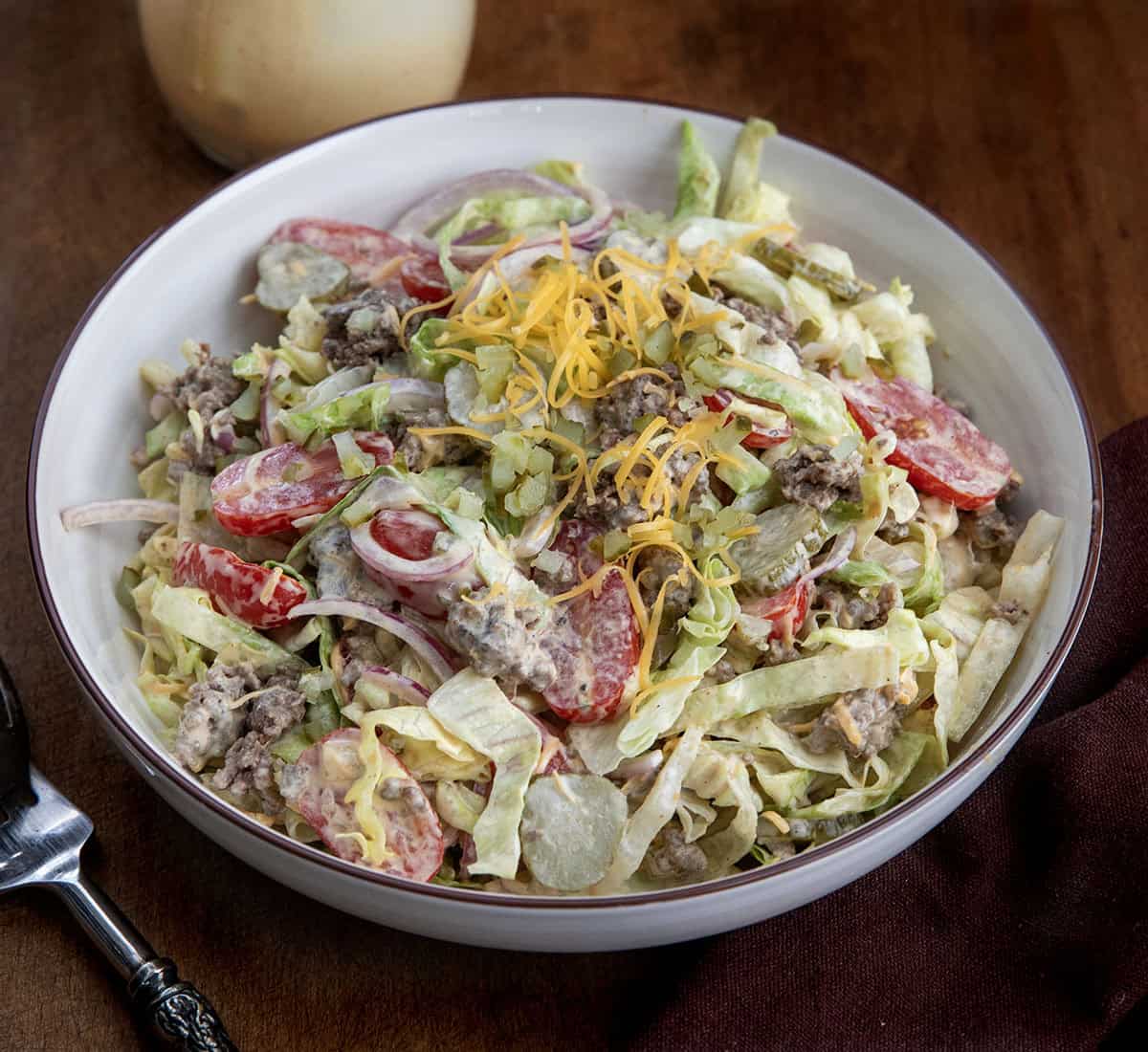 Cheeseburger Salad in a white bowl on a wooden table Cheeseburger Salad in a white bowl on a wooden table.