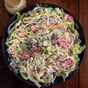 Cheeseburger Salad in a black serving bowl with special sauce on a wooden table from overhead.