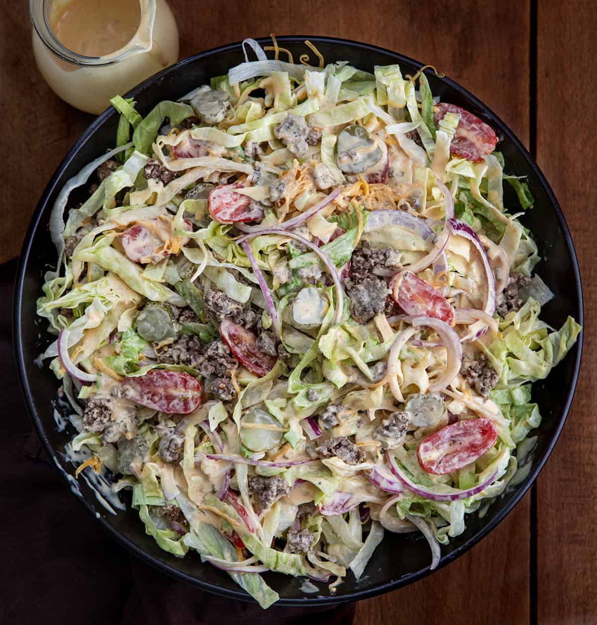 Cheeseburger Salad in a black serving bowl with special sauce on a wooden table from overhead Cheeseburger Salad in a black serving bowl with special sauce on a wooden table from overhead.