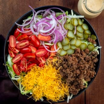 Cheeseburger Salad ingredients in a black serving bowl before being mixed with the special sauce dressing.
