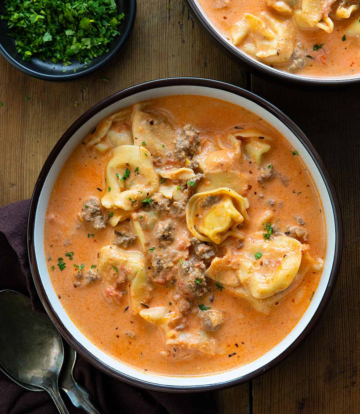 Bowls of Cheesy Hamburger Tortellini Soup on a wooden table from overhead Bowls of Cheesy Hamburger Tortellini Soup on a wooden table from overhead.