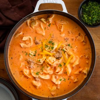 Pot of Cheesy Hamburger Tortellini Soup on a wooden table from overhead.