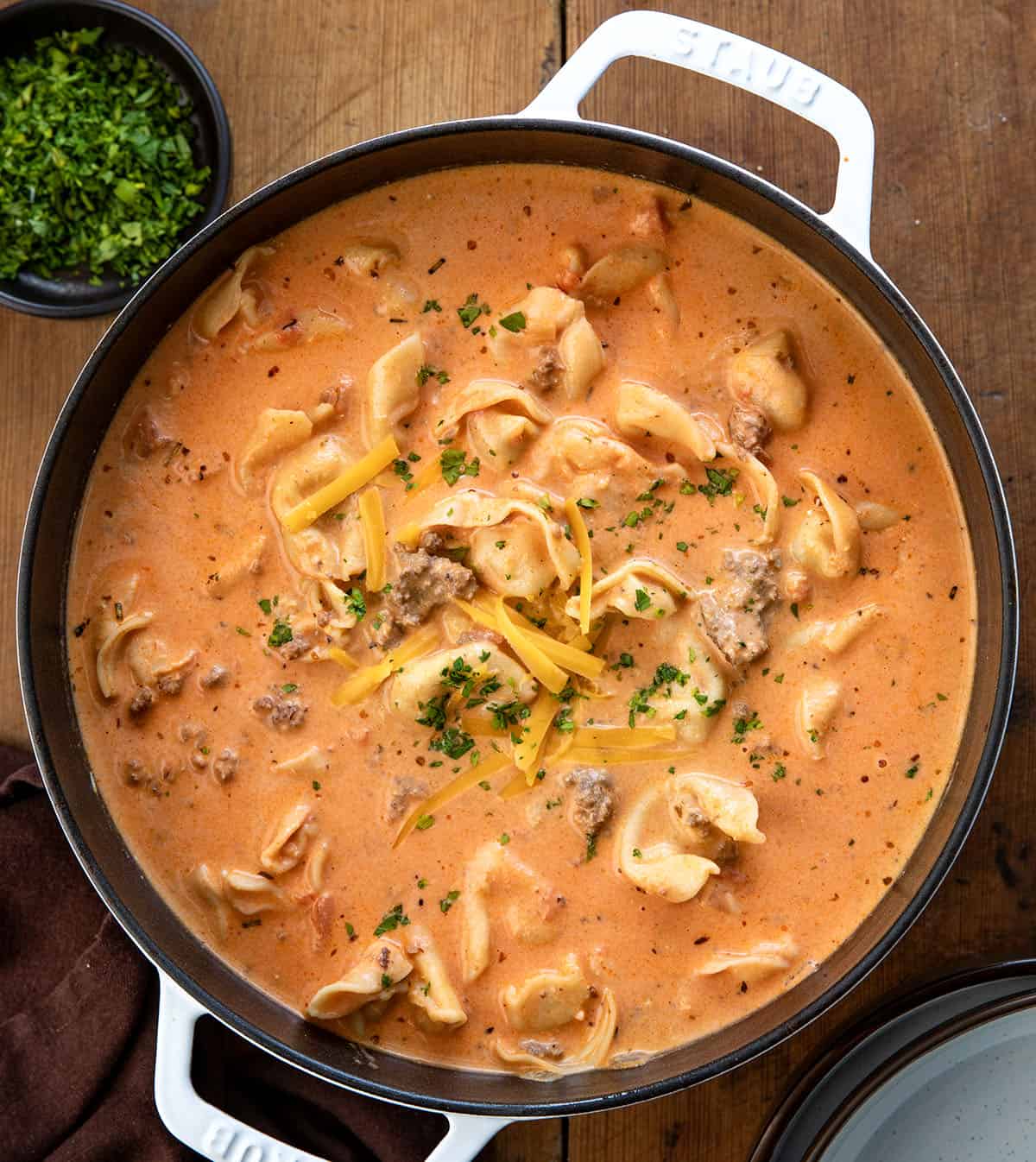Pot of Cheesy Hamburger Tortellini Soup on a wooden table from overhead Pot of Cheesy Hamburger Tortellini Soup on a wooden table from overhead.