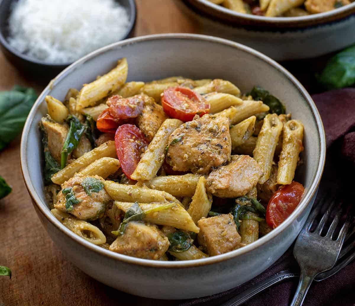 Bowls of Chicken Pesto Pasta on a wooden table close up Bowls of Chicken Pesto Pasta on a wooden table close up.