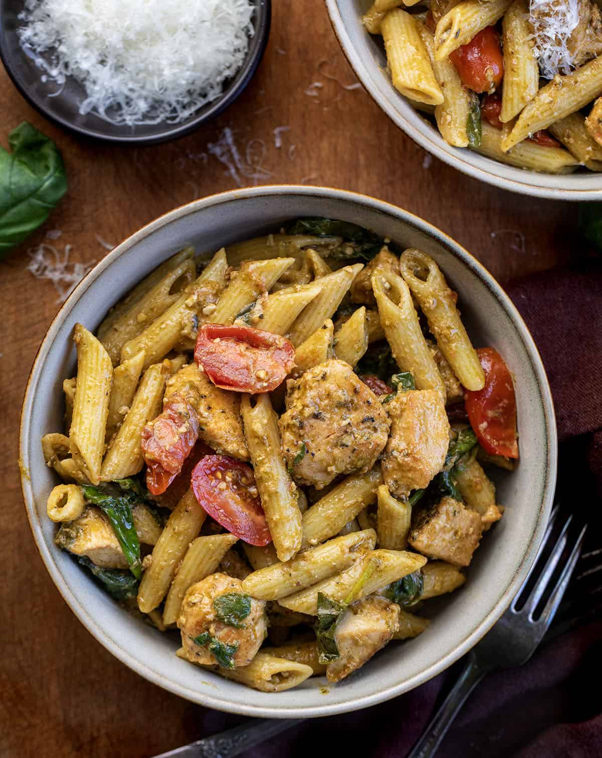 Bowls of Chicken Pesto Pasta on a wooden table from overhead Bowls of Chicken Pesto Pasta on a wooden table from overhead.