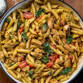 Skillet of Chicken Pesto Pasta on a wooden table from overhead.