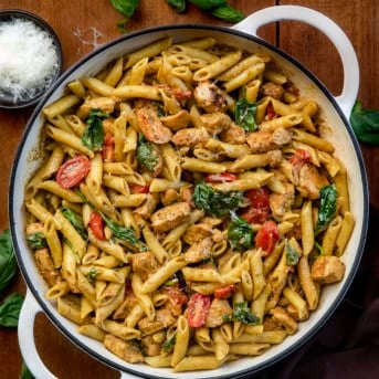 White skillet of Chicken Pesto Pasta on a wooden table from overhead.
