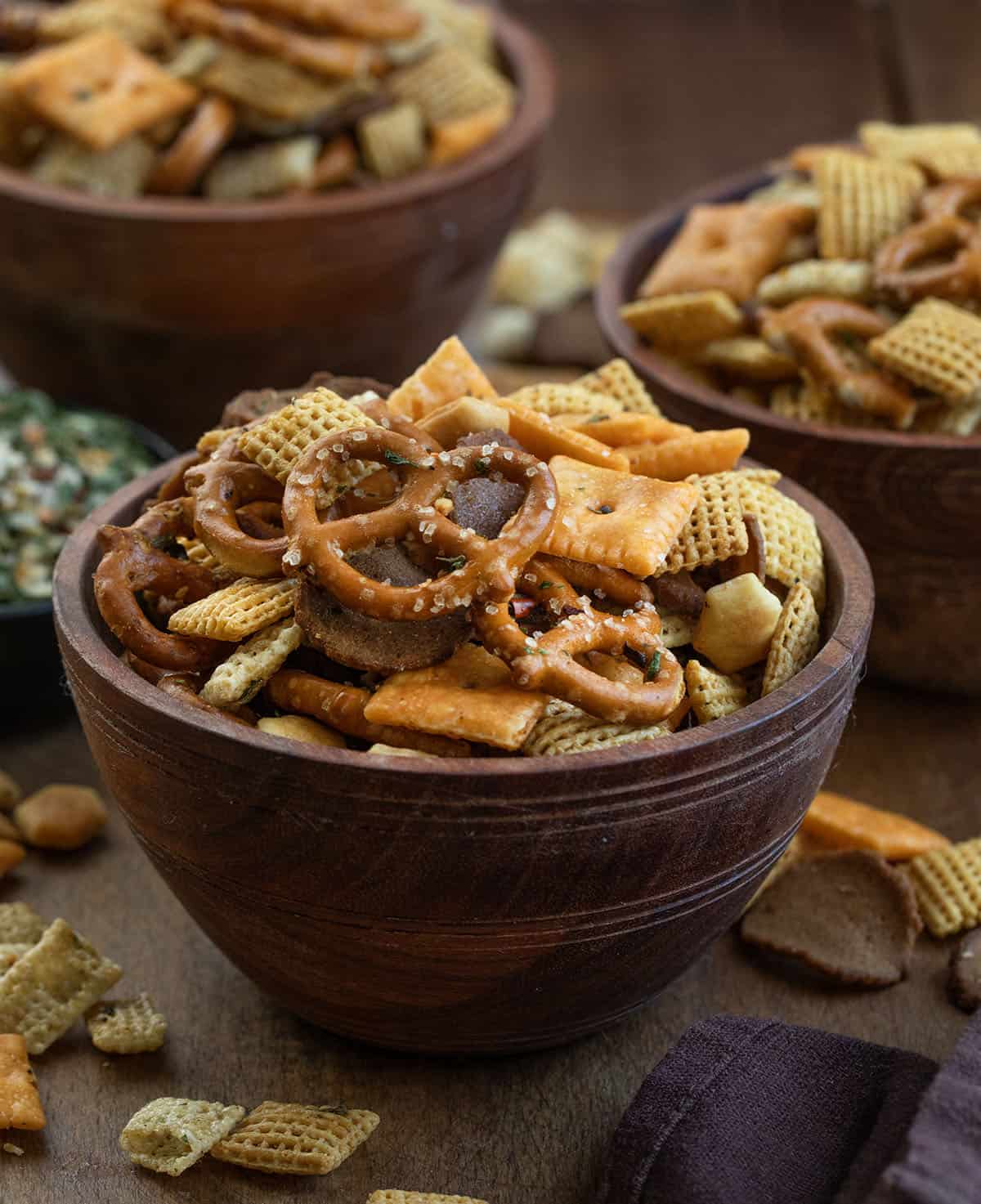 Wooden bowls filled with Cowboy Butter Chex Mix on a wooden table with cowboy butter seasoning in the background Wooden bowls filled with Cowboy Butter Chex Mix on a wooden table with cowboy butter seasoning in the background.