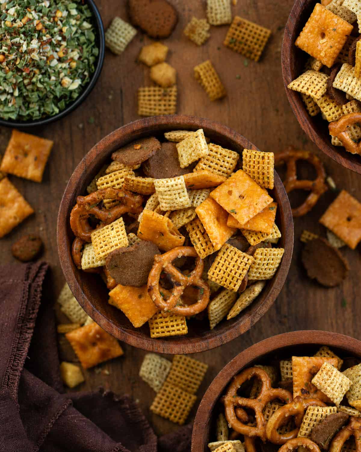 Wooden bowls filled with Cowboy Butter Chex Mix on a wooden table with cowboy butter seasoning from overhead Wooden bowls filled with Cowboy Butter Chex Mix on a wooden table with cowboy butter seasoning from overhead.