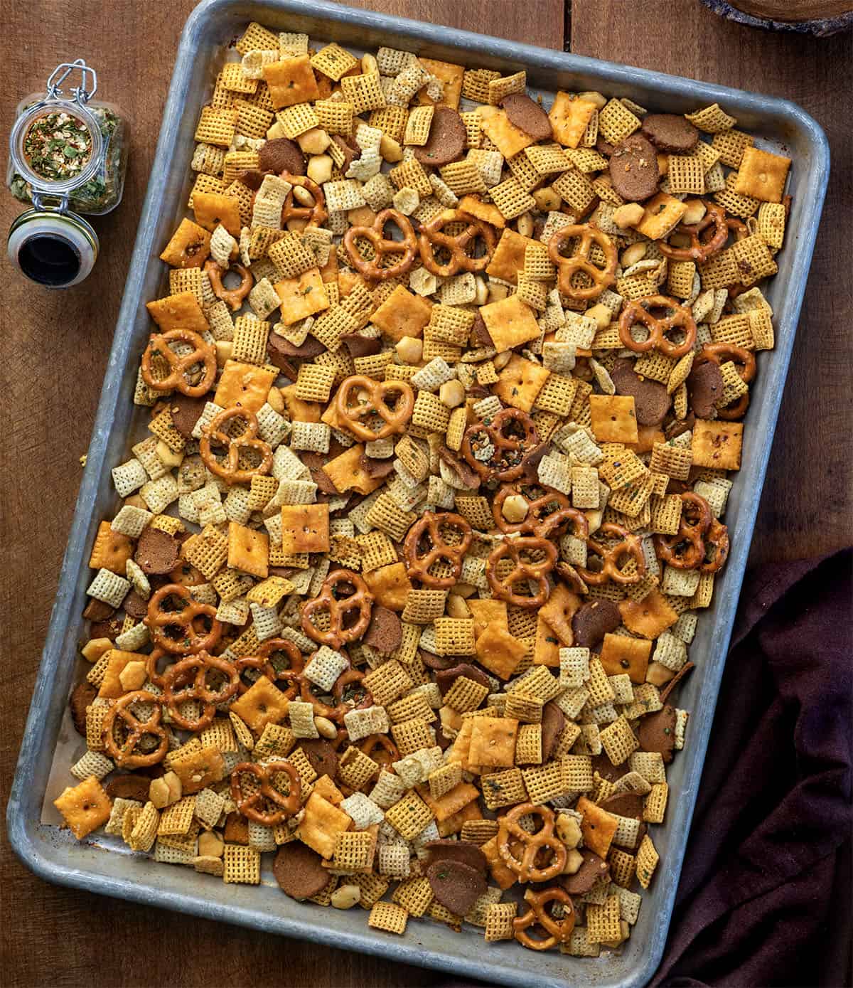 Cowboy Butter Chex Mix in a pan on a wooden table with a jar of cowboy butter seasoning from overhead Cowboy Butter Chex Mix in a pan on a wooden table with a jar of cowboy butter seasoning from overhead.