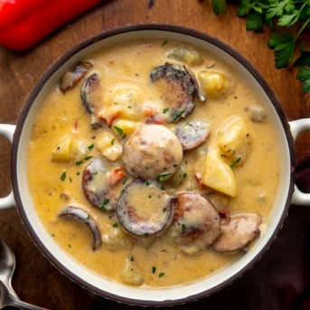 Bowl of Creamy Cajun Potato Soup on a wooden table with red bell pepper from overhead.