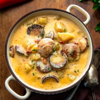 Bowl of Creamy Cajun Potato Soup on a wooden table with red bell pepper.