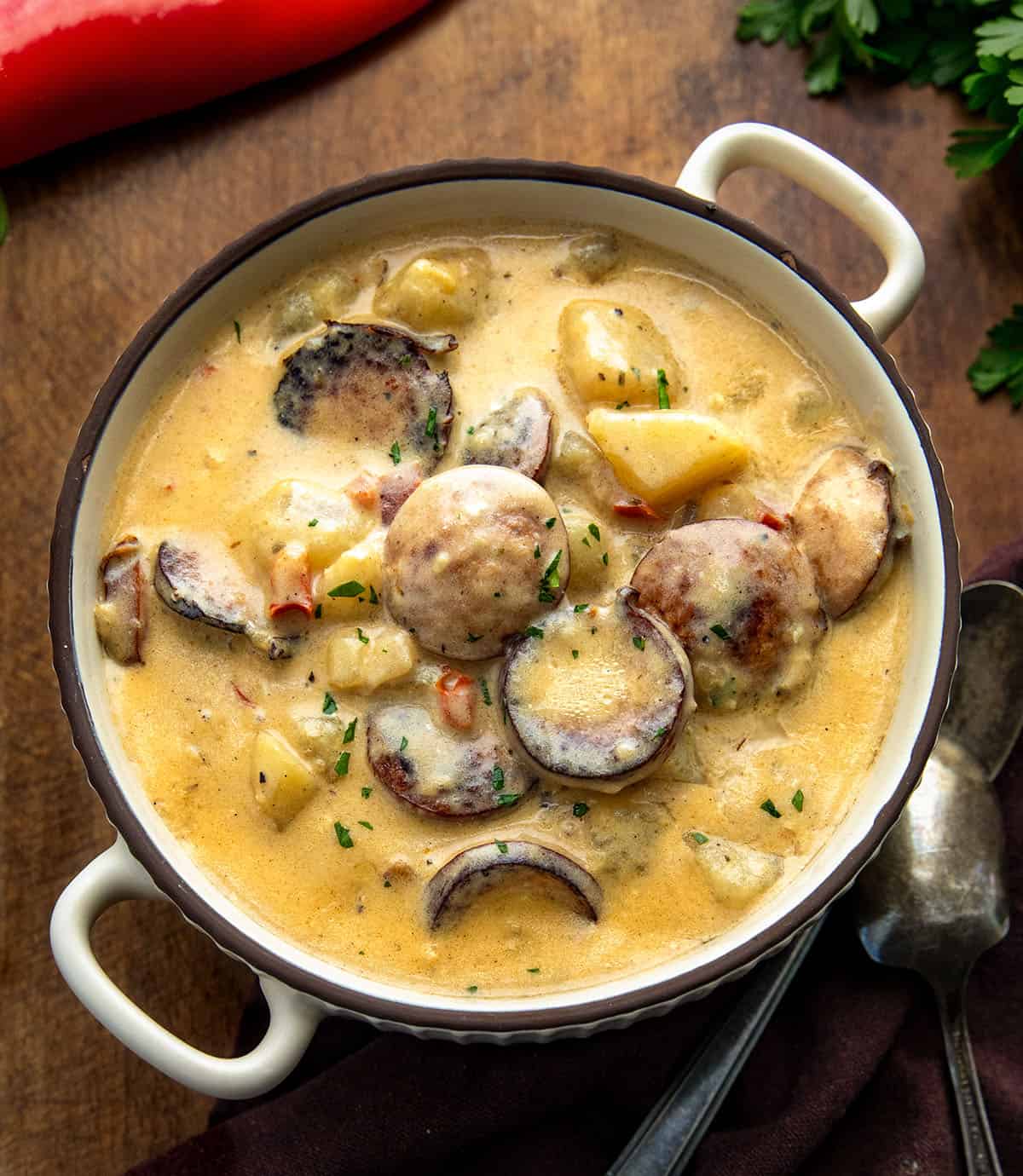 Bowl of Creamy Cajun Potato Soup on a wooden table with red bell pepper Bowl of Creamy Cajun Potato Soup on a wooden table with red bell pepper.