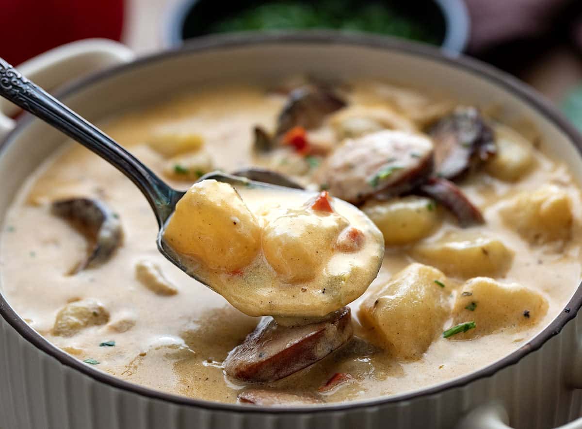 Spoon full of potatoes being held above a bowl of Creamy Cajun Potato Soup Spoon full of potatoes being held above a bowl of Creamy Cajun Potato Soup.
