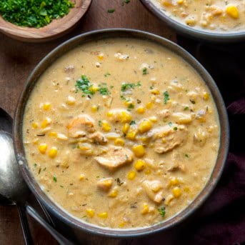 Bowl of Creamy Chicken Corn Orzo Soup on a wooden table from overhead.