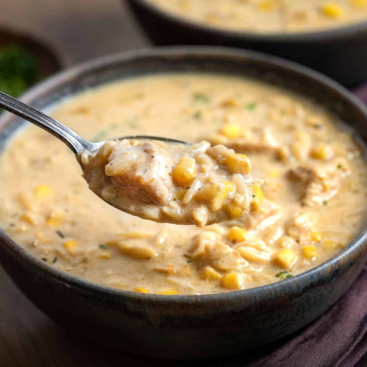 Spoonful of Creamy Chicken Corn Orzo Soup being held above the bowl Spoonful of Creamy Chicken Corn Orzo Soup being held above the bowl.