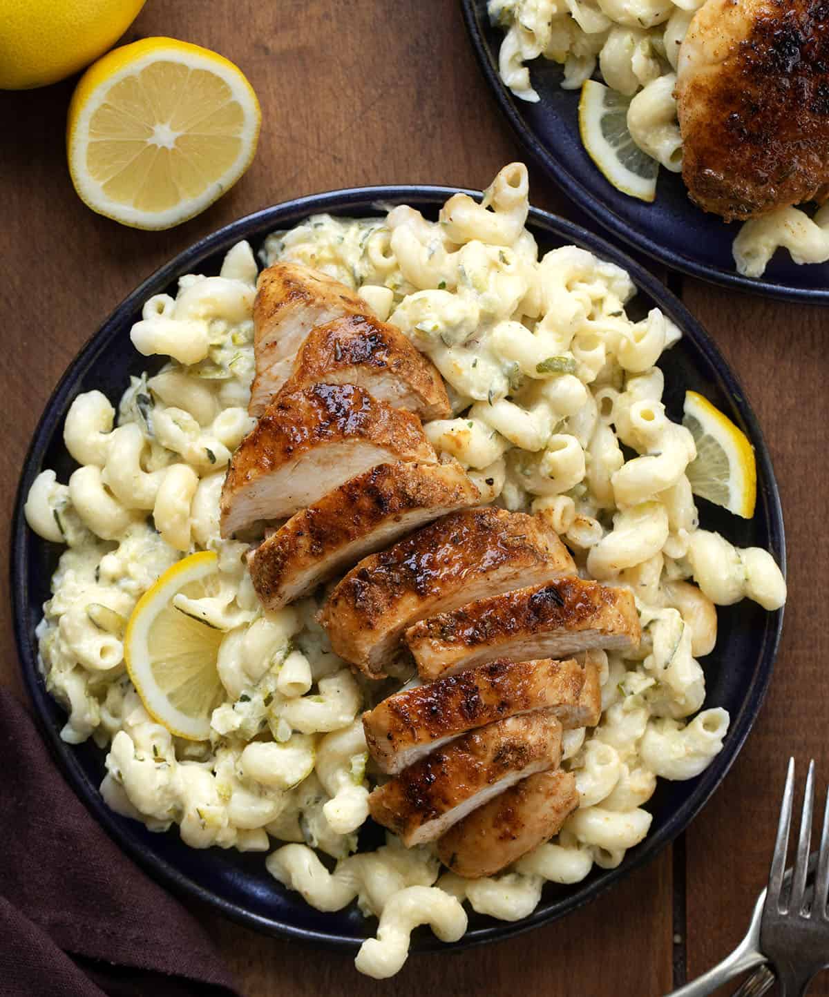 Black plates with Garlic Lemon Chicken Zucchini Pasta on them on a wooden table from overhead Black plates with Garlic Lemon Chicken Zucchini Pasta on them on a wooden table from overhead.