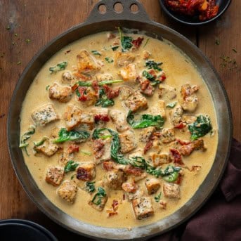 Skillet of Creamy Tuscan Pork Bites on a wooden table from overhead.