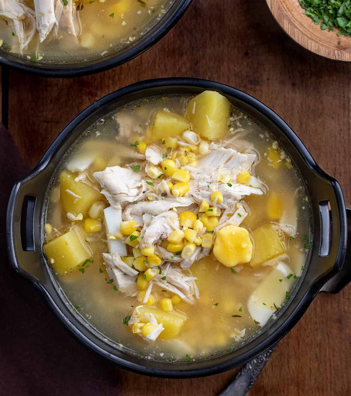 Black bowls of Pennsylvania Dutch Chicken Corn Soup on a wooden table from overhead Black bowls of Pennsylvania Dutch Chicken Corn Soup on a wooden table from overhead.