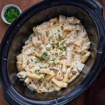 Slow Cooker Chicken Alfredo Pasta on a wooden table from overhead.