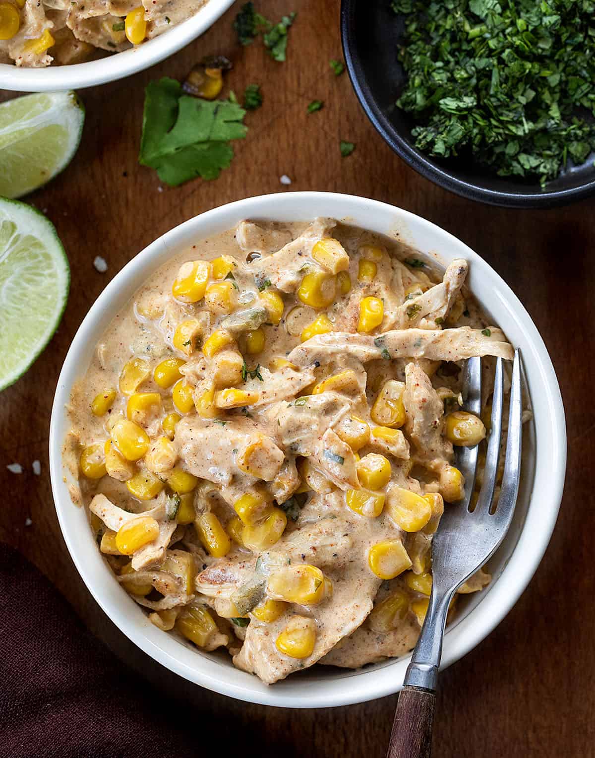 White bowl filled with Slow Cooker Street Corn Chicken on a wooden table White bowl filled with Slow Cooker Street Corn Chicken on a wooden table.