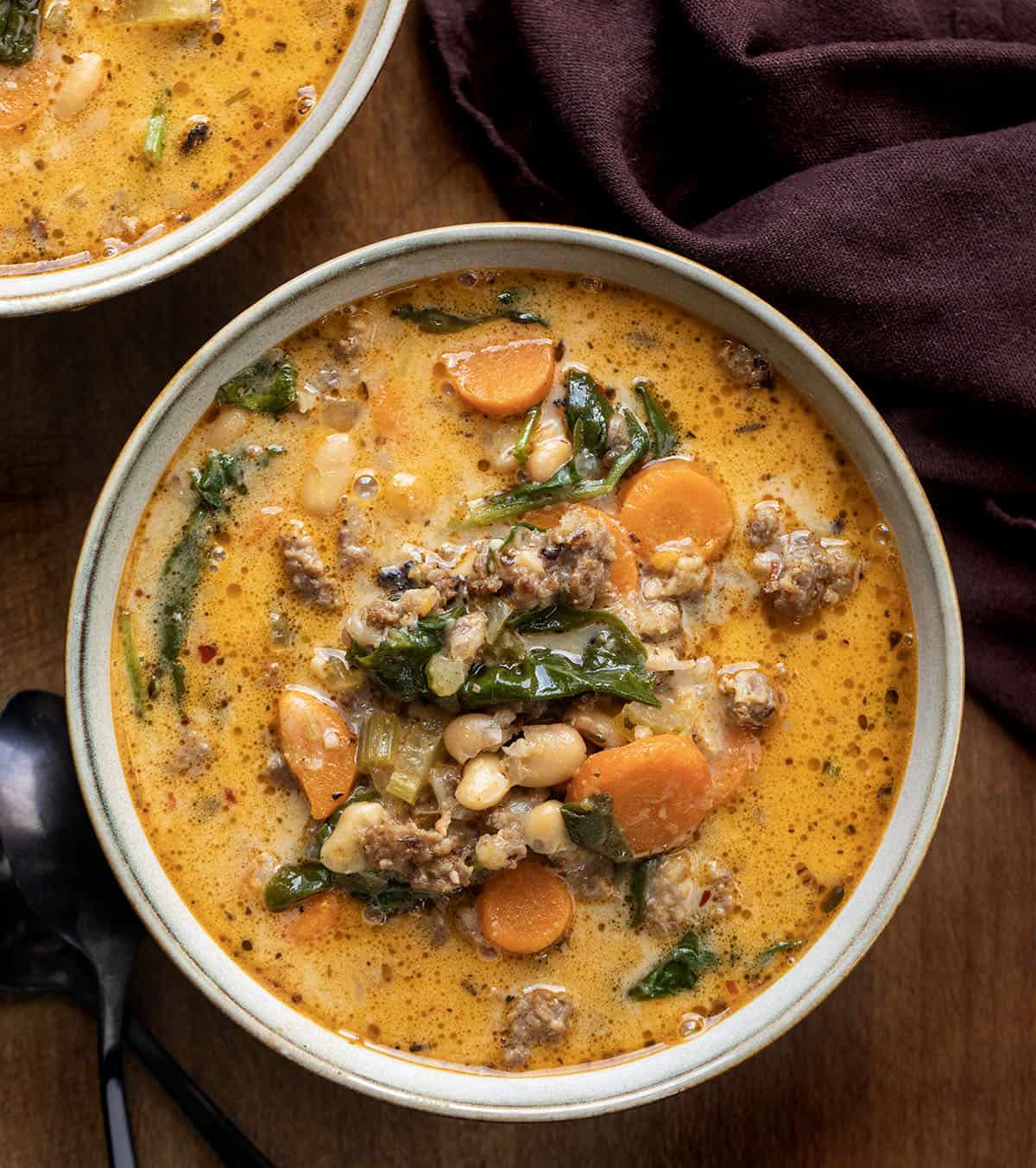 Bowls of Slow Cooker Tuscan White Bean Soup on a wooden table from overhead Bowls of Slow Cooker Tuscan White Bean Soup on a wooden table from overhead.