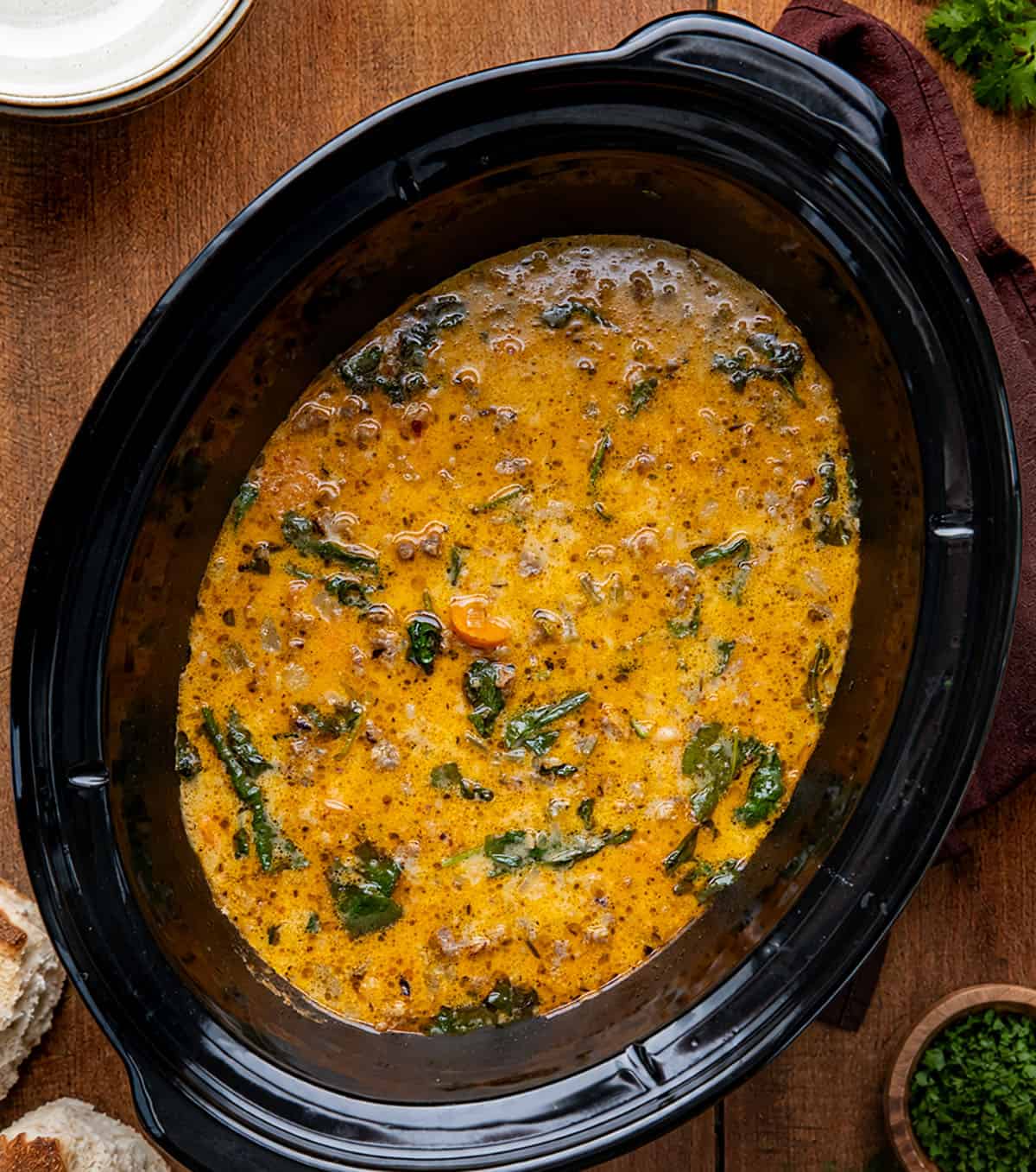 Slow Cooker Tuscan White Bean Soup on a wooden table from overhead Slow Cooker Tuscan White Bean Soup on a wooden table from overhead.