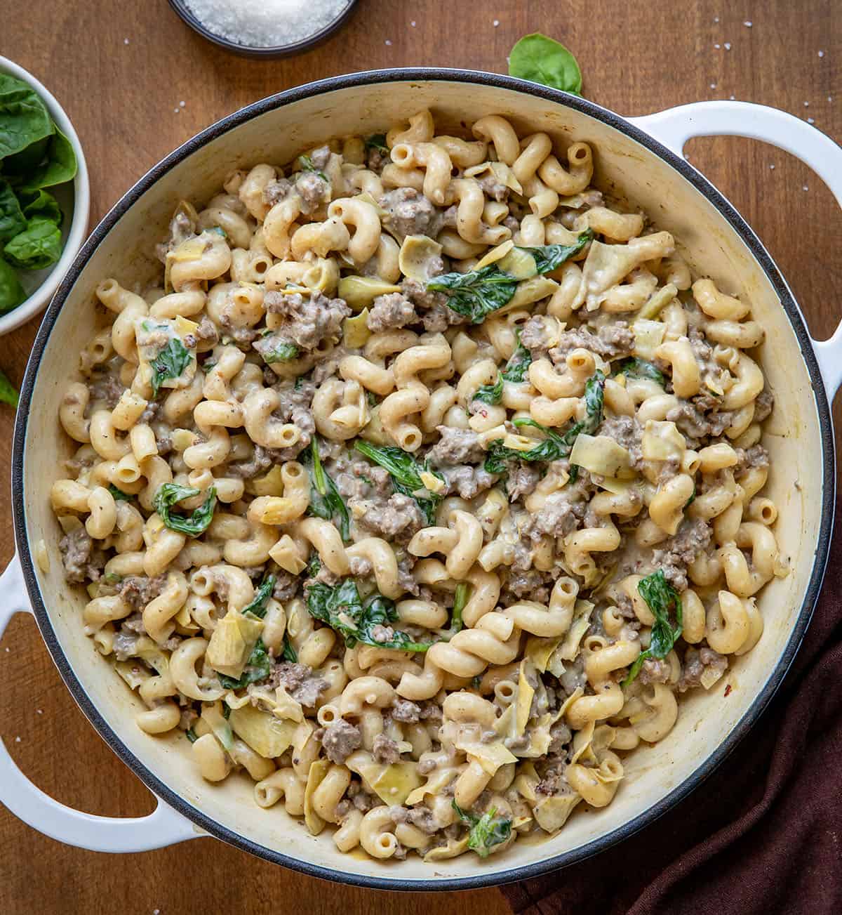 Pot of Spinach Artichoke Hamburger Pasta on a wooden table from overhead Pot of Spinach Artichoke Hamburger Pasta on a wooden table from overhead.