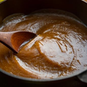 Pot of Apple Butter with a wooden spoon stirring it.