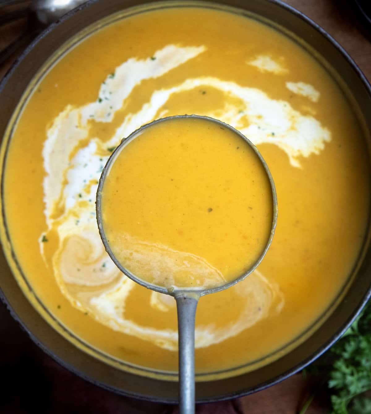 Ladle of Apple Butternut Squash Soup being held above the pot Ladle of Apple Butternut Squash Soup being held above the pot.