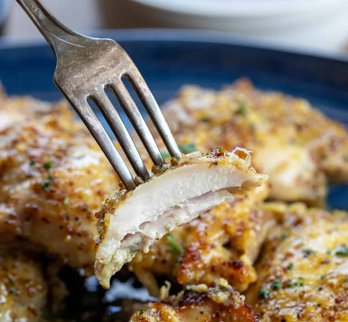 Fork holding a piece of Baked Honey Mustard Chicken Thig Fork holding a piece of Baked Honey Mustard Chicken Thigh.
