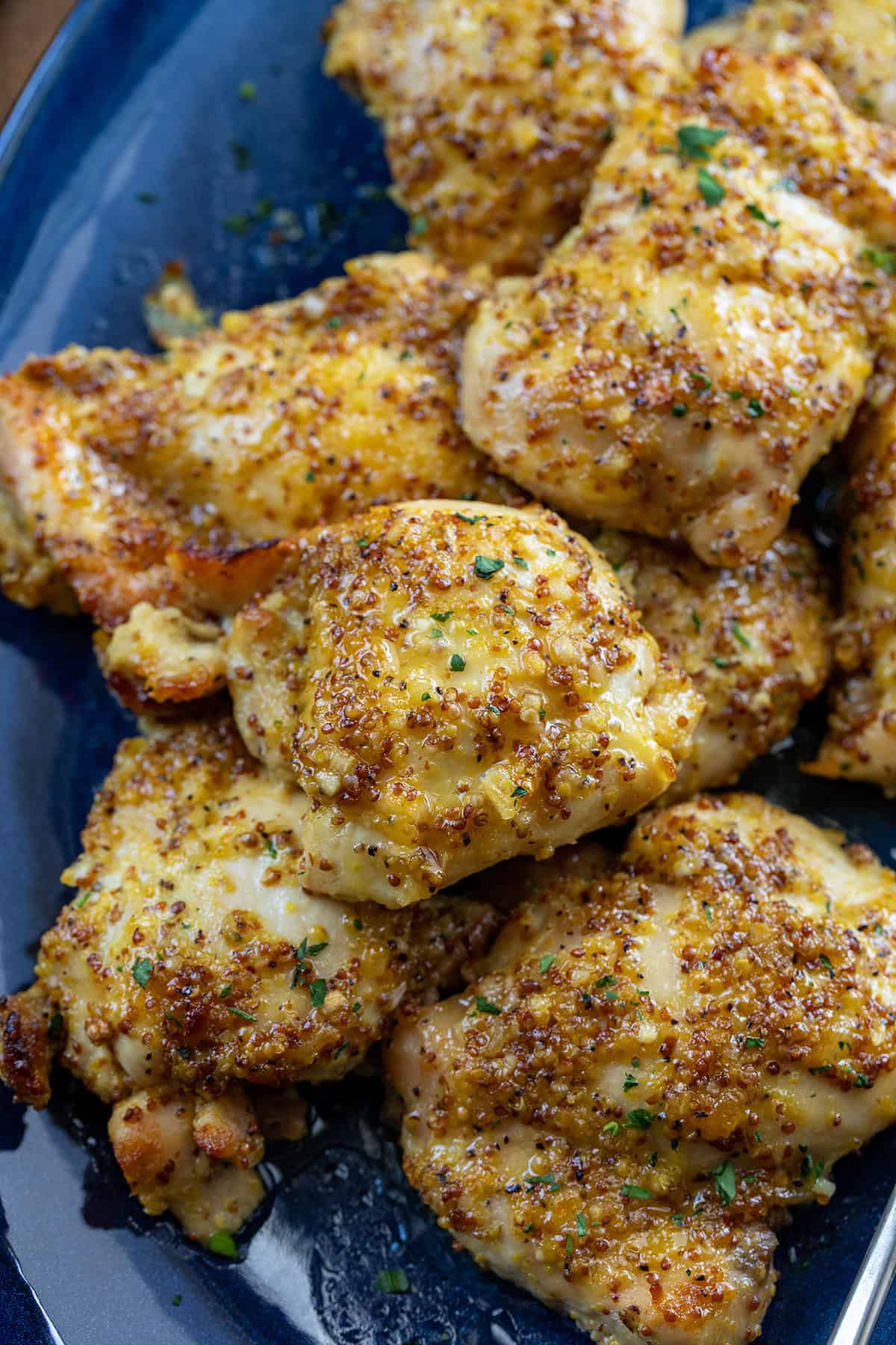 Close up of Baked Honey Mustard Chicken Thighs on a blue platter Close up of Baked Honey Mustard Chicken Thighs on a blue platter.