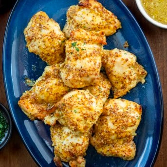 Blue serving platter of Baked Honey Mustard Chicken Thighs on a wooden table from overhead.
