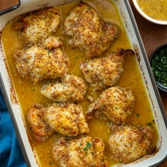 Baked Honey Mustard Chicken Thighs in baking dish on a wooden table from overhead.