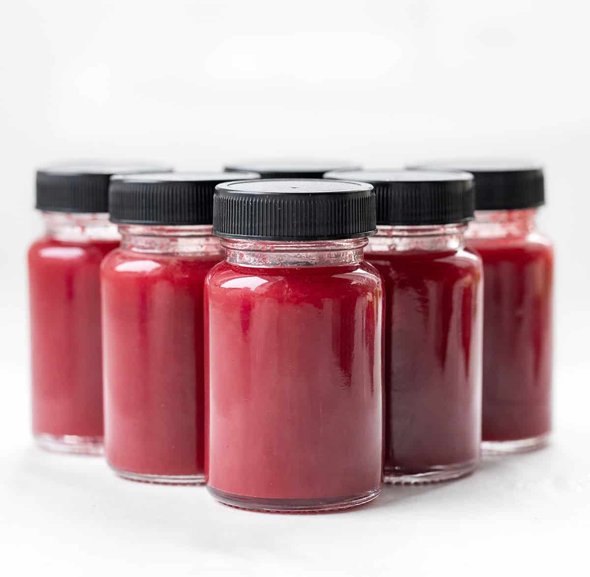 Beet Raspberry Energy Shots lined up on a white table.